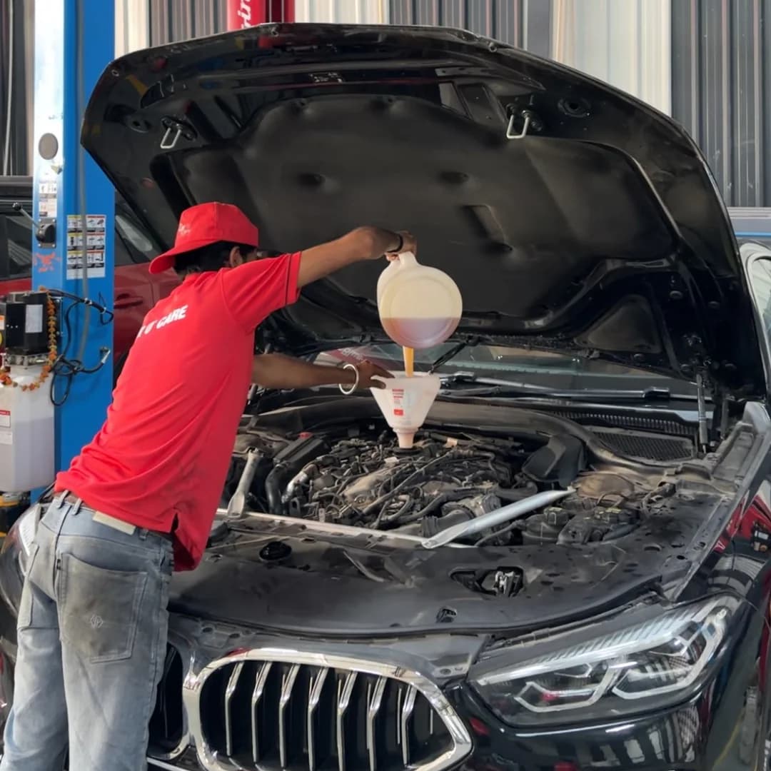 Technician performing periodic maintenance on a BMW engine at THE CAR O CARE workshop in Noida